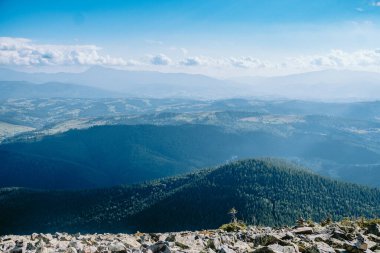 Berrak bir gökyüzünün altındaki yuvarlanan tepelerin ve vadilerin nefes kesici manzarası, sakin bir dağ ortamındaki doğanın güzelliğini gözler önüne seriyor..