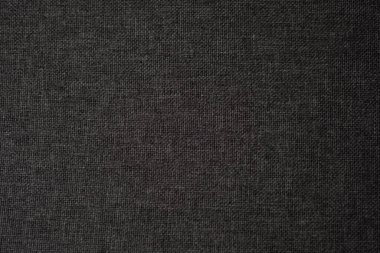 Koyu renk kumaş, ışıkla aydınlatılmış karmaşık dokuma desenleriyle zengin bir doku sergiliyor..