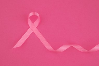 Pembe kurdele, göğüs kanseri farkındalığını temsil eden parlak pembe bir yüzeye dayanır..
