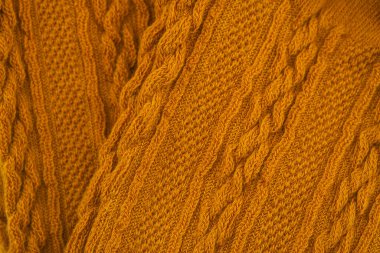 Zengin hardal sarısı rengini ve detaylı dokuları gösteren örgü kumaşının yakın görüntüsü.