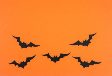 Bats are scattered across a vibrant orange backdrop, creating a festive autumn atmosphere. clipart