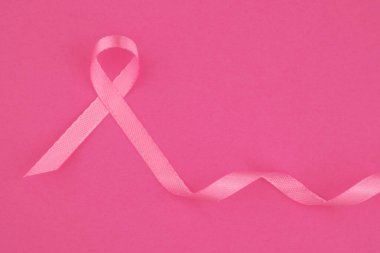 Pembe bir kurdele canlı pembe bir arka plana dayanır, kanser farkındalığını temsil eder..