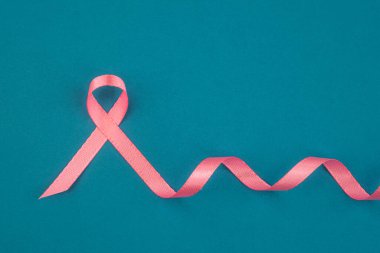 Pembe bir kurdele, göğüs kanseri farkındalığını arttırmak için turkuaz bir yüzeye sanatsal olarak yerleştirilir..