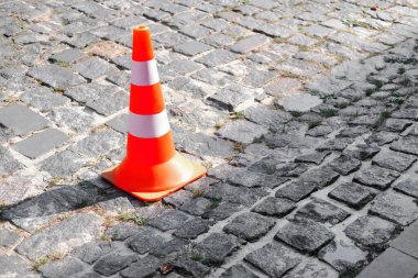 Parlak turuncu bir trafik konisi bir kaldırım taşı caddesine kurulmuştur..