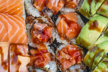 Renkli bir suşi rulosu ve sashimi karışımı. Taze somon ve avokado sergileniyor..