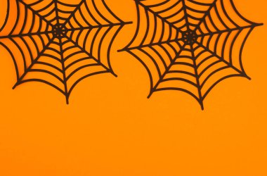 Decorative black spider webs are arranged on a vibrant orange background, ideal for Halloween. clipart