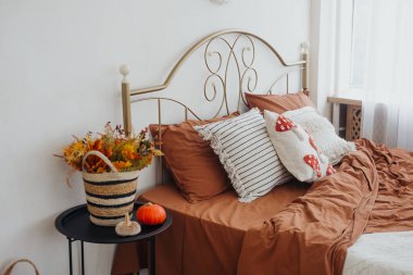 Sonbahar renkleriyle süslenmiş, rahat bir yatak odası ve çiçek aksanlı..