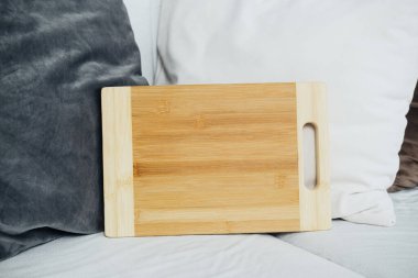 Yumuşak yastıklarla çevrili bir kanepeye yerleştirilmiş bambu kesme tahtası rahat bir atmosfer yaratıyor..