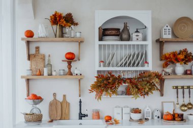 Mutfakta, raflarda ve tezgahlarda kabaklar ve renkli yapraklarla sonbahar dekorasyonu yer alıyor..