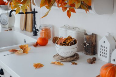 Sonbahar yaprakları, balkabakları ve dekoratif aksanlarla süslenmiş parlak bir mutfak tezgahı..
