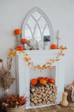 Balkabakları, yapraklar ve şöminenin üstündeki aynayla süslü bir sonbahar düzenlemesi..