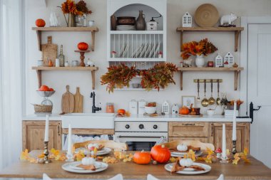 Balkabaklarıyla süslenmiş sıcak bir mutfak, mevsimlik yapraklar ve sonbahar için şenlikli bir yemek düzeni..