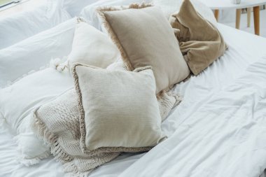 Parlak bir yatak odasında yatağın üzerinde yastık ve battaniye bulunur..