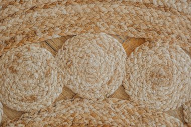 Karmaşık dokuma desenleri içeren yuvarlak saman paspaslar kapalı bir ahşap zeminde serilmiştir..