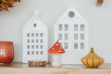 A cozy display of ceramic houses, a mushroom figure, and a gourd on a wooden shelf. clipart