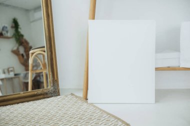 Yaratıcı bir çalışma alanındaki boş bir tuval ve dekoratif bir ayna..