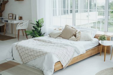 Geniş pencerelerden gelen doğal ışıkla dolu, rahat bir yatak odası..