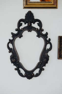 Karmaşık tasarımı olan zarif bir siyah çerçeve düz beyaz bir duvara monte edilmiştir..