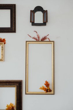 Sonbahar yapraklarıyla süslenmiş zarif boş bir çerçeve zarif bir şekilde bir duvara yaslanır..