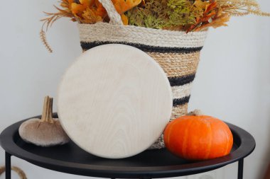 Küçük bir balkabağı ve bir sepet sonbahar çiçeğinin yanında bir tahta kesme tahtası yatıyor..