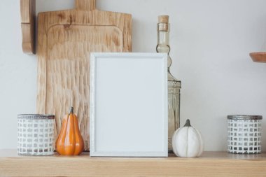 Balkabakları, mumlar ve ahşap bir yüzey üzerinde boş bir çerçeve ile rahat bir mutfak düzenlemesi..