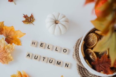 Mevsimlik dekor, canlı sonbahar yaprakları, küçük beyaz bir balkabağı ve sıcak bir selamlama içerir..