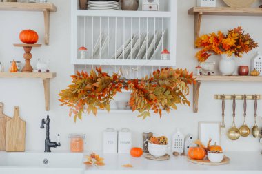 Sonbahar süslemeleriyle süslenmiş rahat bir mutfak, balkabakları ve renkli yapraklar da dahil..