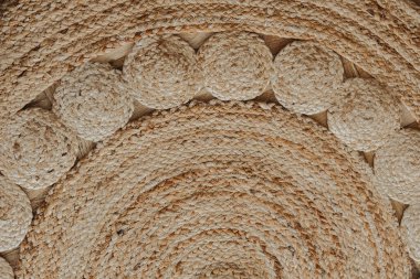 Doğal liflerden yapılmış dokulu dairesel bir paspas ahşap bir zemine sabitlenir..