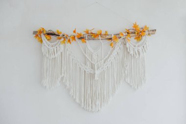 A decorative macrame piece featuring vibrant autumn leaves, enhancing the room's decor. clipart