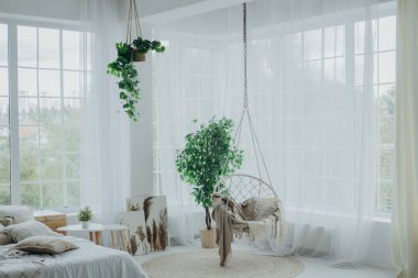 Konforlu bir yaşam alanı. İçinde sallanan bir sandalye ve bereketli bitkiler var. Doğal ışık geniş pencerelerden süzülerek, dinlenmek için mükemmel sakin bir atmosfer yaratır..