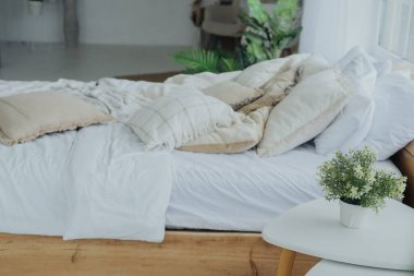 Parlak ve davetkar bir yatak odasında çeşitli yumuşak yastıklarla süslenmiş bir yatak vardır. Oda doğal ışık ve yeşillikle dolu. Rahatlatıcı bir atmosfer yaratıyor..