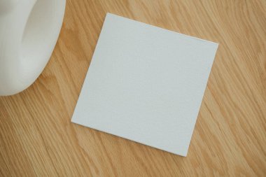 Düz beyaz karo, yumuşak ışıklandırmayla aydınlatılan, desenli tasarımı ve zıt renkleri gözler önüne seren pürüzsüz ahşap bir yüzeye dayanır..