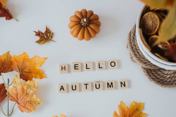 Уютная композиция с осенними листьями, ромашкой и деревянными буквами, выражающими осеннюю радость.