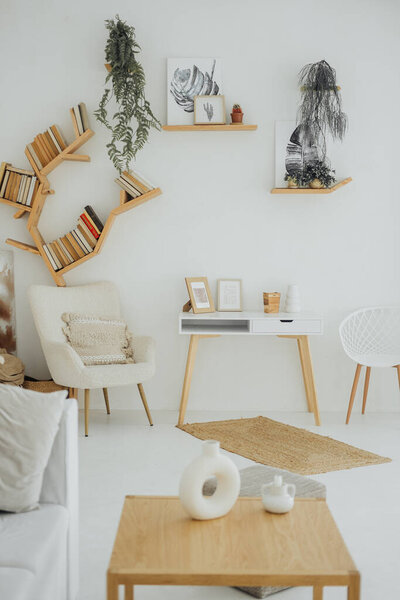A stylish living room features creative wooden shelves filled with books, a light-colored armchair, and decorative plants, creating a cozy and inviting atmosphere.