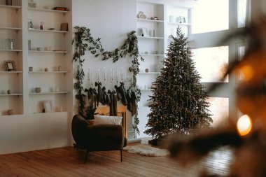 Oturma odasında güzel dekore edilmiş bir Noel ağacı, rahat bir sandalye ve şömineye asılmış çoraplar yer alıyor. Doğal dekor bu şık kış ortamında sıcaklık katıyor..