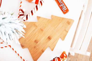 A bamboo platter shaped like a Christmas tree rests on a table, surrounded by festive decorations including candy canes and a welcome sign, capturing the holiday spirit. clipart