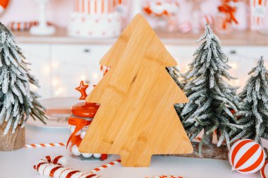 A wooden Christmas tree stands prominently among snowy pine trees and red and white candies. The warm atmosphere captures the spirit of holiday season festivities and decorations. clipart