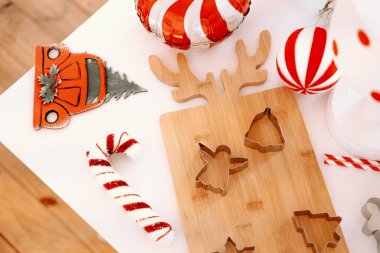 Colorful holiday-themed cookie cutters and decorations are arranged on a clean tabletop. A cheerful atmosphere is created with striped candy canes and festive ornaments nearby. clipart