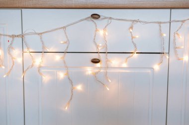 Narin sicim lambaları mutfak dolabı boyunca zarifçe örtülmüş, sıcak bir ortam yaratıyor. Yumuşak parıltı, rahat atmosferi güçlendirir. Akşam toplantıları ya da sıradan yemekler için mükemmeldir..