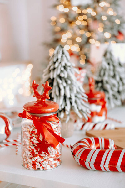 Уютная праздничная обстановка с баночкой, наполненной красочными конфетками и полосатыми леденцами. Снежные мини-деревья и теплые огни добавить праздничное прикосновение к веселому расположению.
