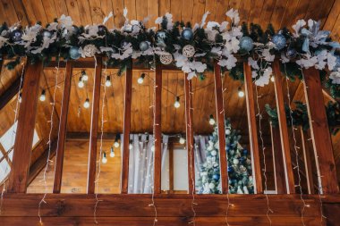 Güzel dekore edilmiş bir iç mekan süslemeleri ve sıcak ışıklarla süslenmiş bir çelenk içerir. Sıcak ahşap döşeme bayram kutlamaları için mükemmel bir şenlik ortamı yaratıyor..