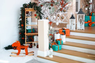 Bu nefis tatil ortamında ahşap sallanan bir atın yanı sıra canlı paketlenmiş hediyeler ve tatil süslemeleri de yer alıyor. Davetkar merdiven şenlikli aksanlarla süslenmiş..