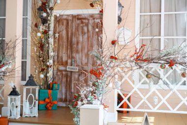 A warm, inviting front porch is adorned with holiday decorations, including garlands, ornaments, and gift-wrapped presents, creating a cheerful atmosphere for the festive season. clipart