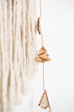 Ağaç şeklindeki ahşap süsler bir sicim teline asılarak tatil dekorasyonu veya sıcak ev estetiği için ideal desenli bir arka plana karşı şenlikli bir atmosfer yaratıyor..