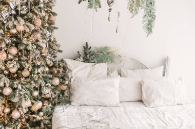 Bu davetkar uzay zarif süslemelerle süslenmiş bir Noel ağacını sergiliyor. Yatak yumuşak, nötr renkli yastıkları ve rahat dokuları barındırıyor ve sıcak bir atmosfer yaratıyor..