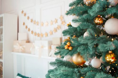 Güzel dekore edilmiş bir Noel ağacı belirgin bir şekilde duruyor, altın ve beyaz süsler içeriyor..