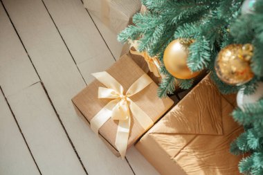 Renkli dekorasyonlar yemyeşil bir Noel ağacını süslüyor, şenlikli bir atmosfer yaratıyor, güzel paketlenmiş hediyeler ise sabırla beyaz ahşap bir zeminde, açılmayı bekliyor..