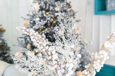 Delicate white frosty branches are elegantly arranged in the foreground, while a beautifully decorated Christmas tree glows softly in the background, creating a warm holiday atmosphere. clipart