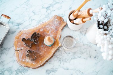 The countertop is set for baking, featuring cookie cutters, rolling pins, and a small wooden dough cutter. A touch of festive decor and tools are neatly arranged for holiday treats. clipart