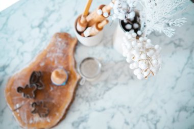 A marble countertop features holiday baking tools, cookie cutters, and decorative winter accents. The scene captures a warm, inviting atmosphere perfect for festive culinary creations. clipart